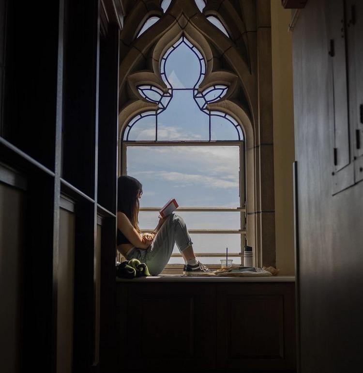 Student reading a book near window in Cathedral of Learning