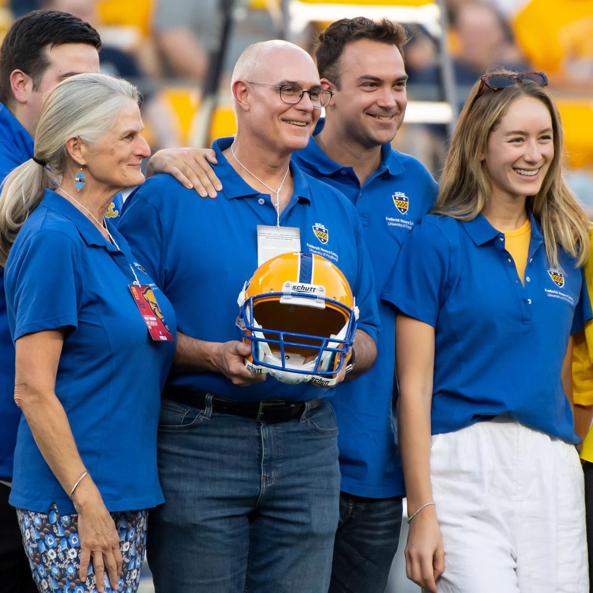 David Frederick holding a football helmet stands along with his wife, Sophie Lynn (second from left), and his family during the Backyard Brawl.